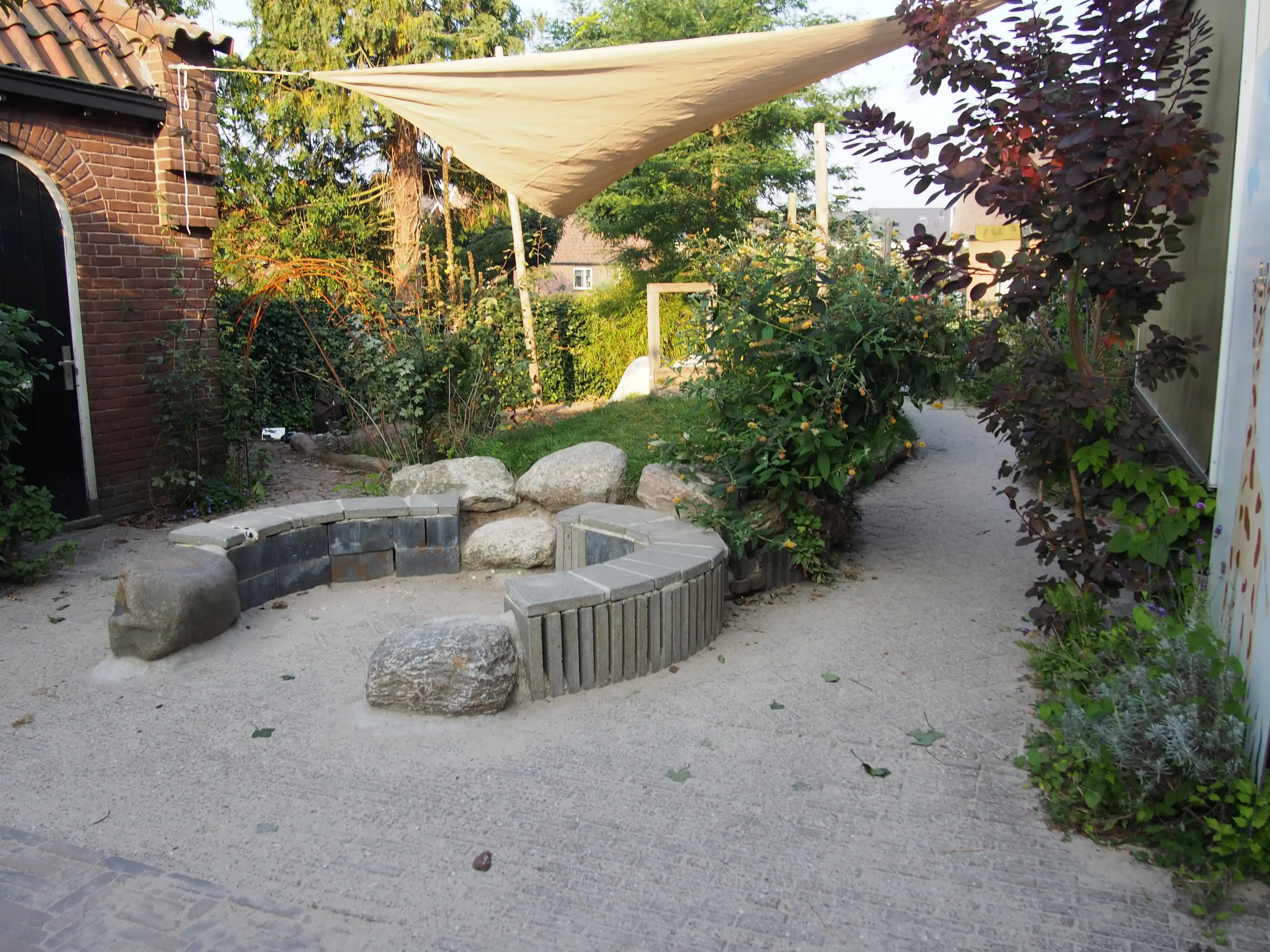 Cour végétalisée avec voile d'ombrage et rochers